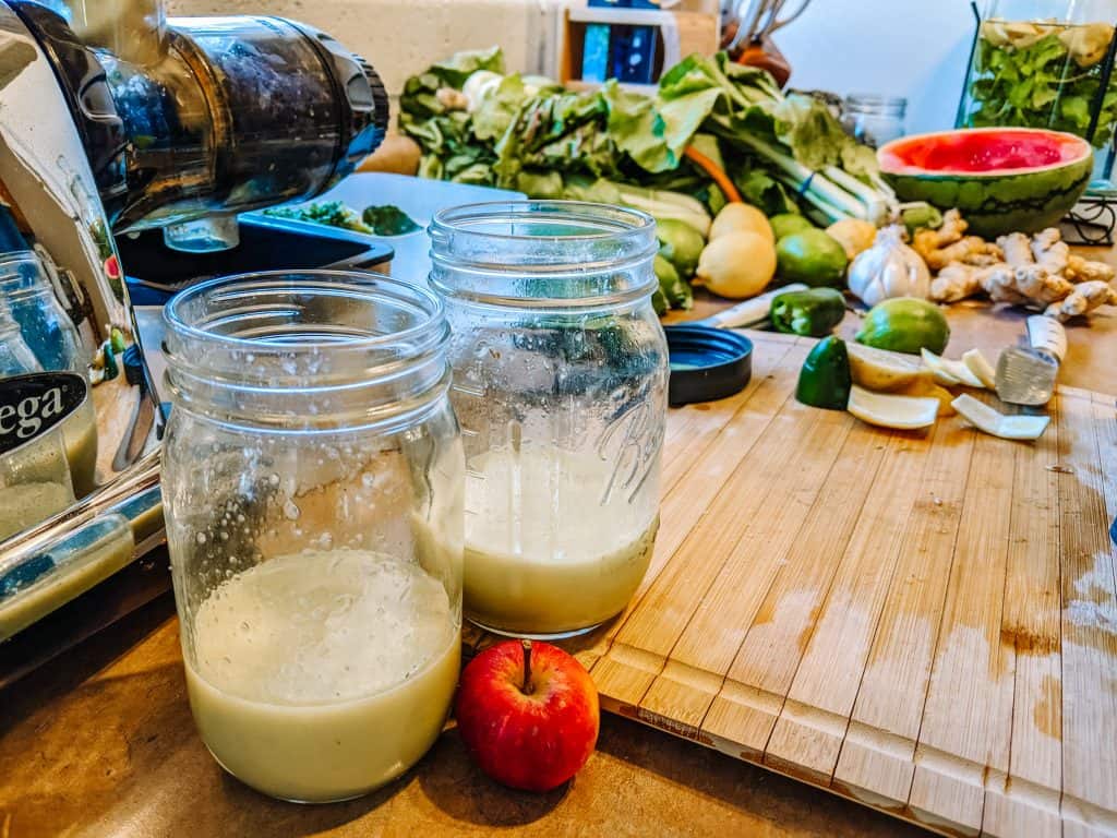 Juicing fresh produce with repurposed glass jars for storage, demonstrating simple zero waste swaps in my kitchen to reduce plastic waste and embrace sustainable living.