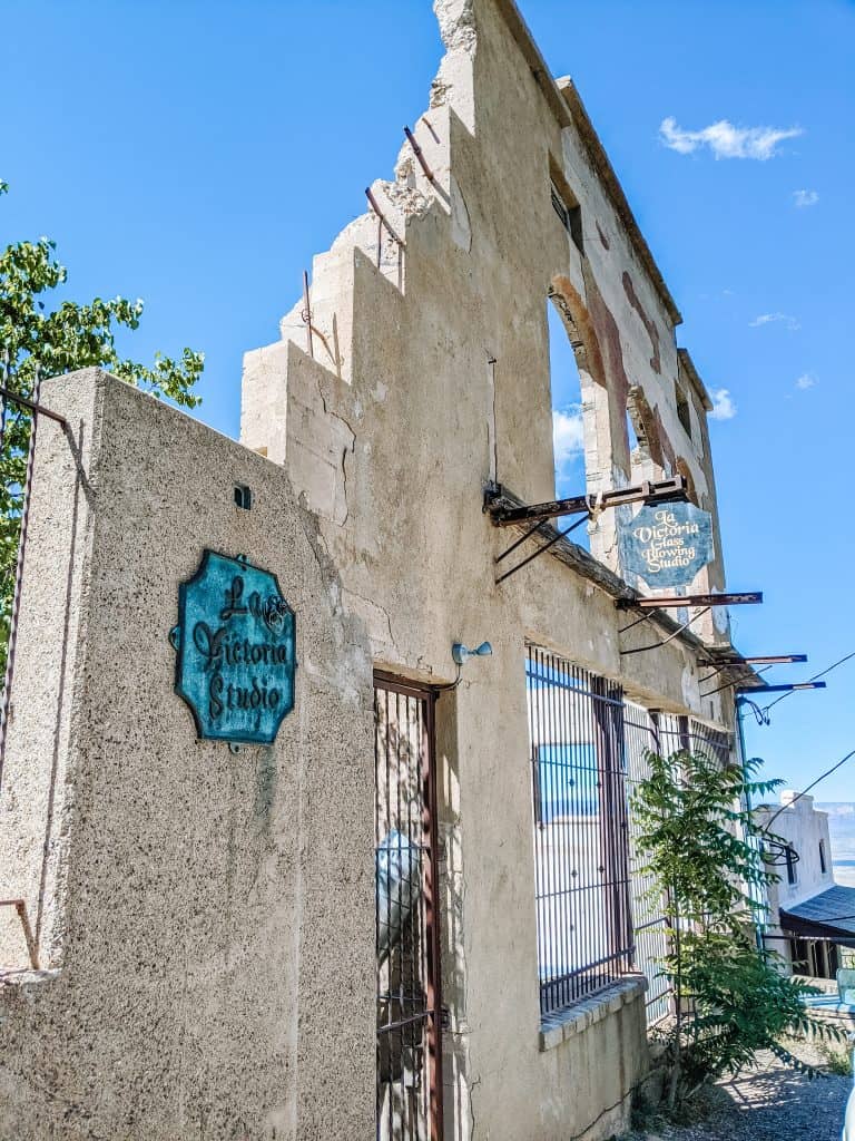 When you visit Jerome Ghost Town, you'll see this rustic facade of La Victoria Studio, a partially crumbling building with an old sign. The bright blue sky and scattered greenery.