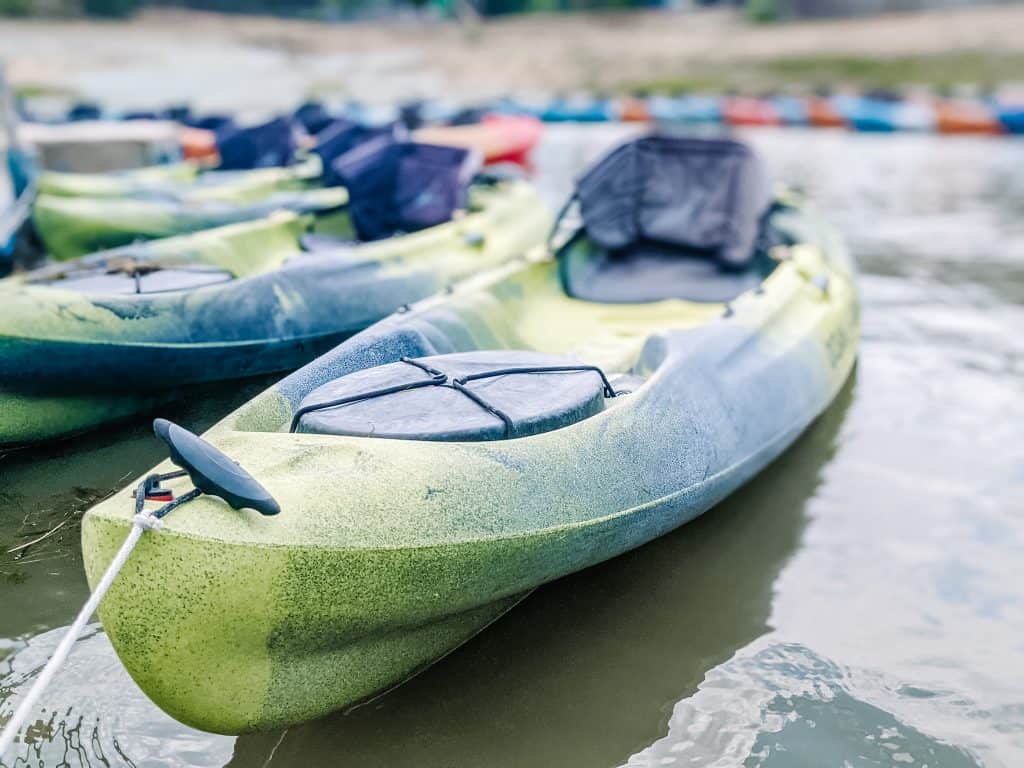 In the City of Big Bear, kayaks float on the calm lake, ready for adventure. The green and blue kayaks are tied together.