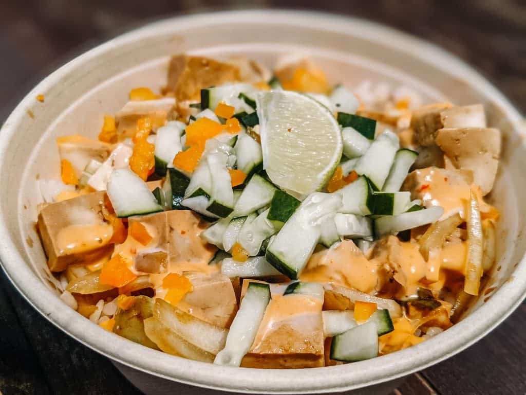 This bowl from the City of Big Bear features rice topped with tofu, diced bell peppers, cucumbers, and a wedge of lime, all drizzled with a creamy, tangy sauce.