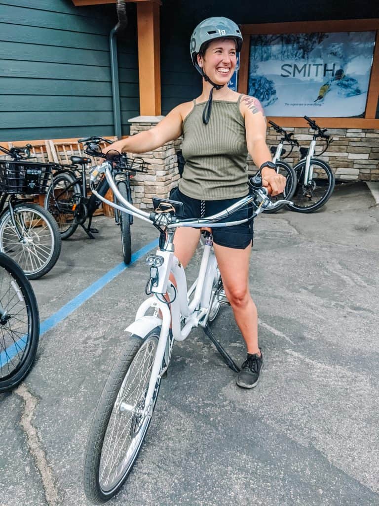 Here I am, enjoying a bike ride in the City of Big Bear. Wearing a helmet and smiling, I'm ready to explore the routes and trails. The weather is perfect, and the backdrop of bikes and local shops adds to the charm of the adventure.