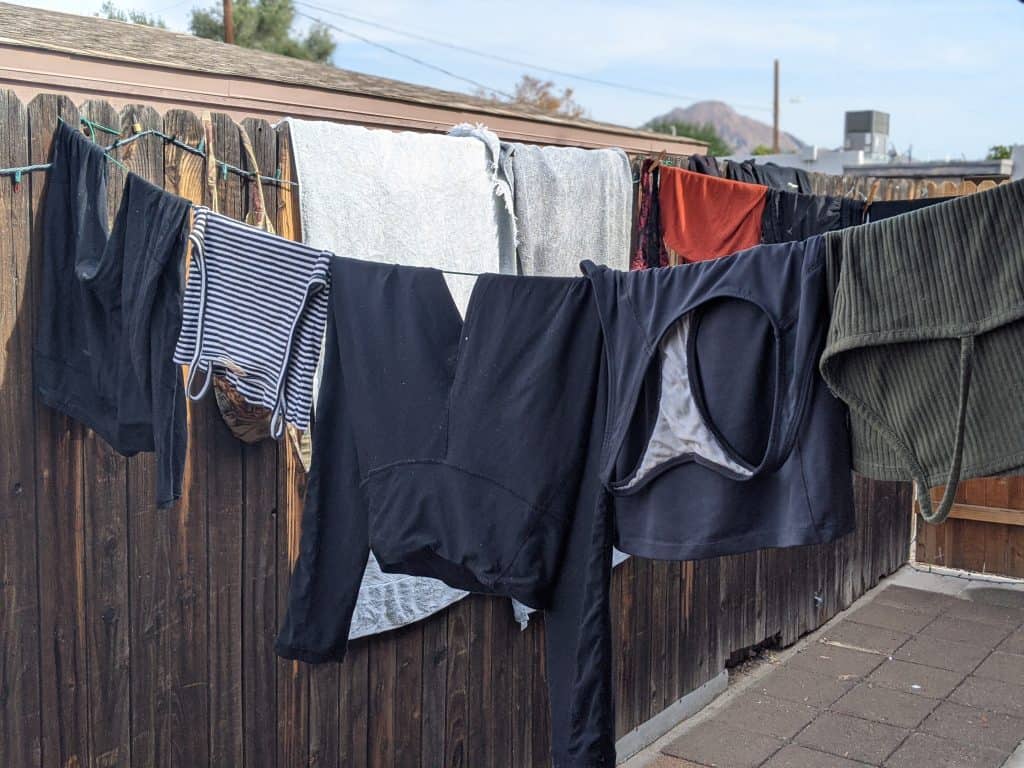 These are my clothes hanging on a clothesline outdoors, drying in the sun, highlighting a practical aspect of van life when considering the camper van cost for laundry solutions.