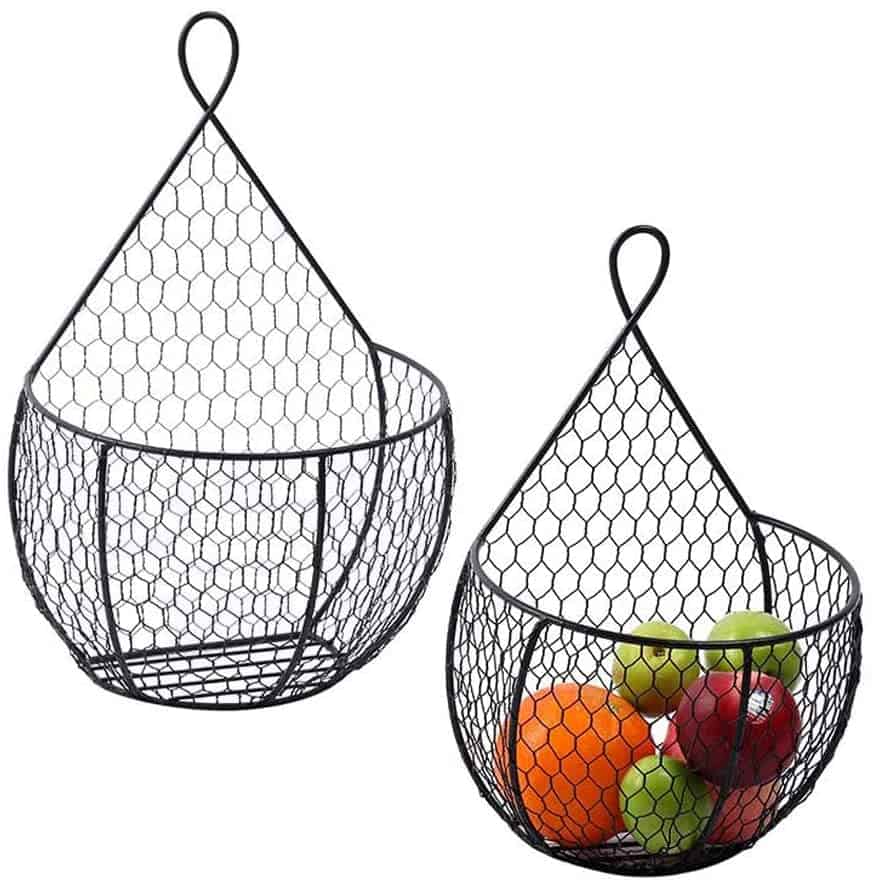 There are two black wire hanging baskets, one of which contains various fruits. These baskets are perfect for a camper conversion van, offering a stylish and practical way to store fruits, vegetables, or other small items, keeping them organized and easily accessible while saving valuable counter space.