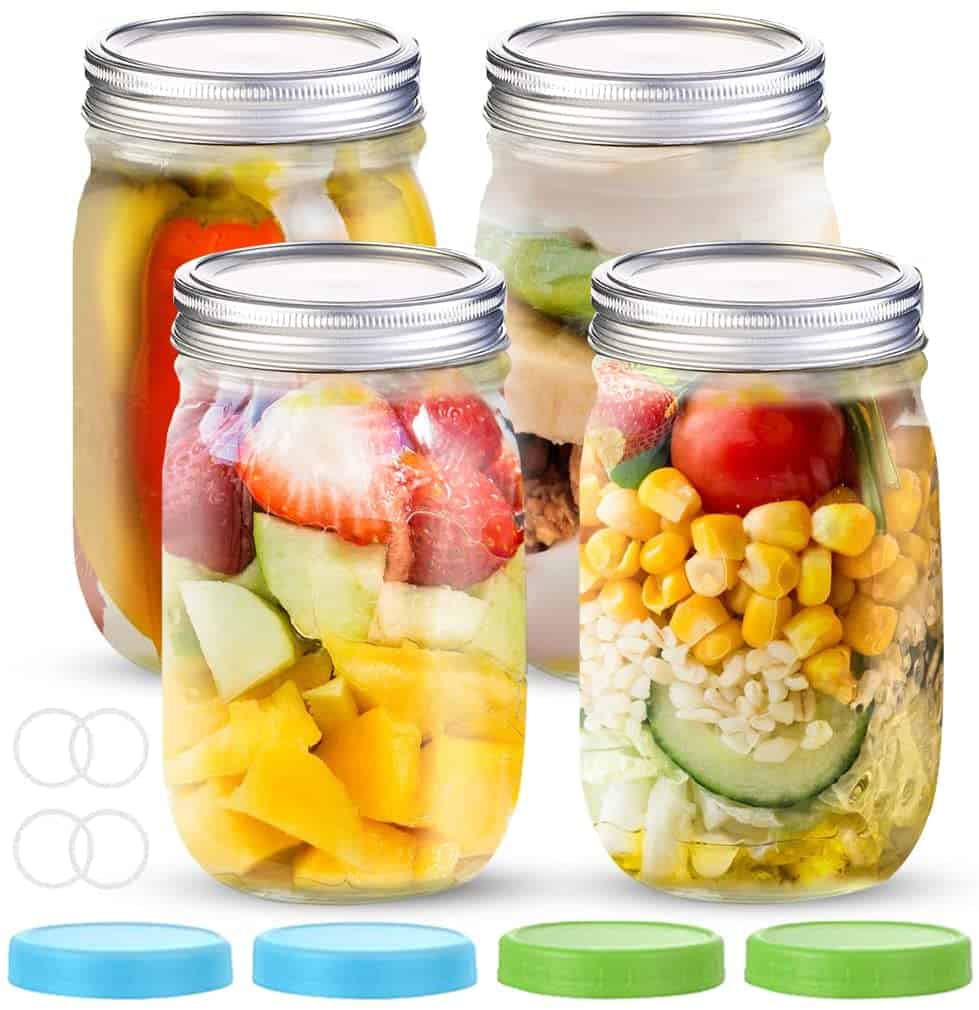 Four mason jars filled with colorful, fresh ingredients like mangoes, strawberries, cucumbers, tomatoes, and corn. These jars, complete with blue and green lids, are a perfect way to store salads or snacks in a camper conversion van