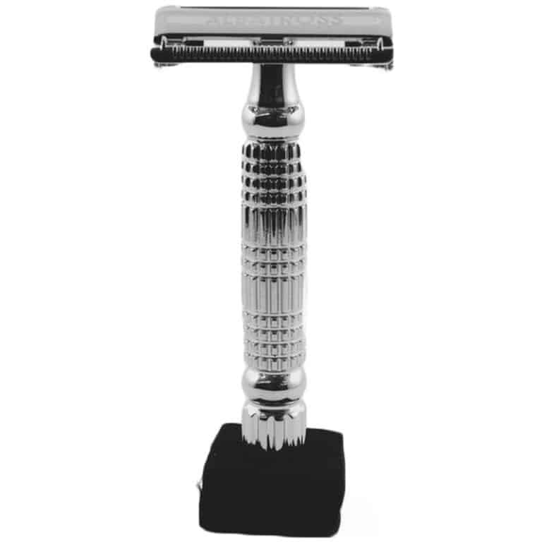 A sleek and stylish metal safety razor, ideal for a sustainable gift guide. The razor has a shiny, chrome finish with a textured handle for a firm grip. It stands upright on a small black stand.