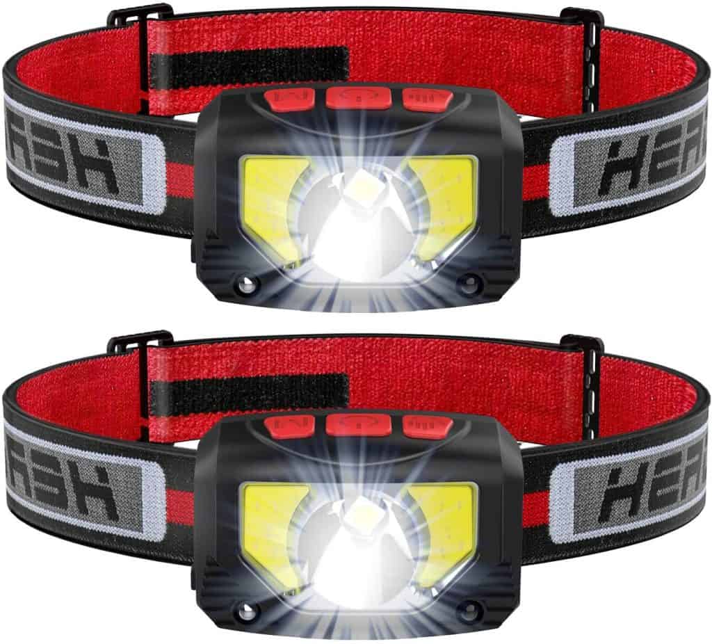 A two headlamps with bright LED lights and adjustable red and black straps, which are considered hike essentials for illuminating trails during night hikes or early morning starts.