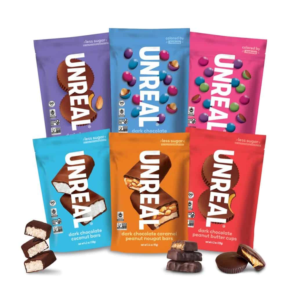 A variety of Unreal snacks, including colorful packs of chocolate-covered treats and coconut bars, which are perfect snacks you can bring on an airplane to satisfy your sweet tooth.