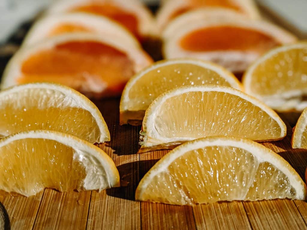 Slices of oranges and grapefruits are neatly arranged on a wooden surface, offering a refreshing and hydrating option for snacks you can bring on an airplane.