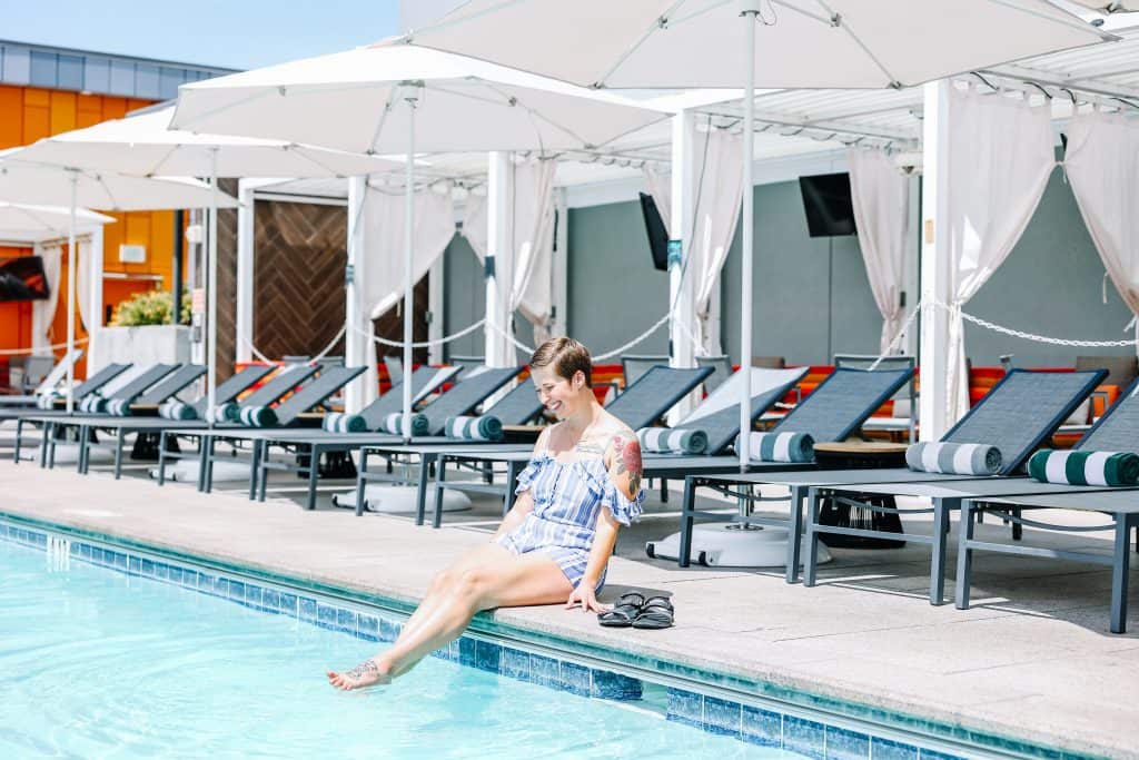 That's me sitting by a hotel pool, dipping my feet in the water, with lounge chairs and umbrellas behind me, enjoying a relaxing vacation made possible with the best travel credit card.