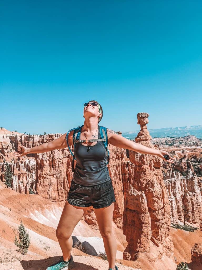 Taken at Bryce National Park, you see me standing triumphantly with my arms outstretched, with rock formations around me. The clear blue sky contrasts sharply with the reddish-orange spires. My backpack and hiking attire hint at the adventure.