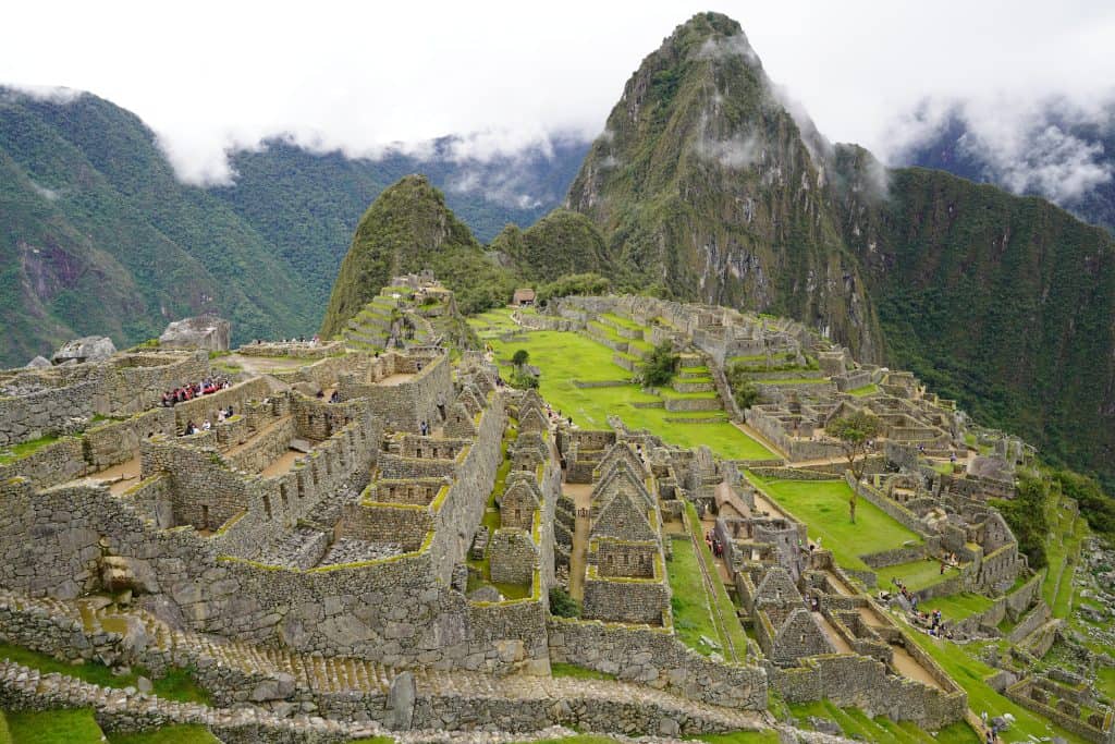 The ancient Incan city of Machu Picchu, nestled in the Andes Mountains of Peru, with its iconic stone structures, terraced fields, and lush green surroundings, making it one of the top places to visit in Peru.