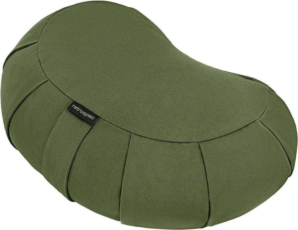 A green, kidney-shaped meditation cushion, ideal for providing comfort during long meditation sessions at a Vipassana Meditation Retreat.