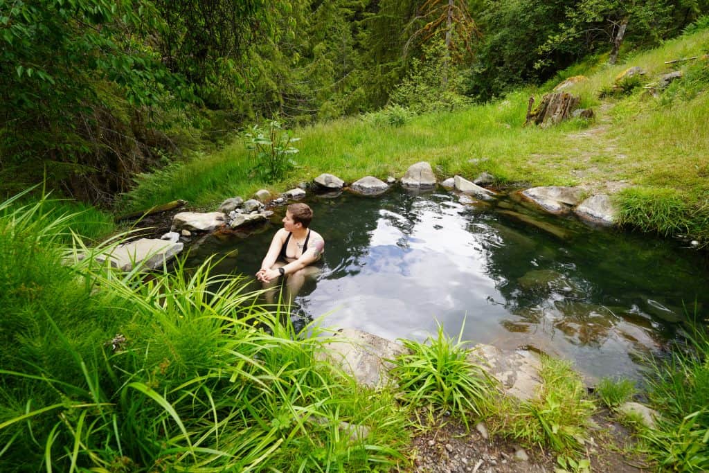 It's me relaxing in a natural hot spring, surrounded by lush green foliage, highlighting the peaceful experience that comes with a well-prepared hot springs packing list.