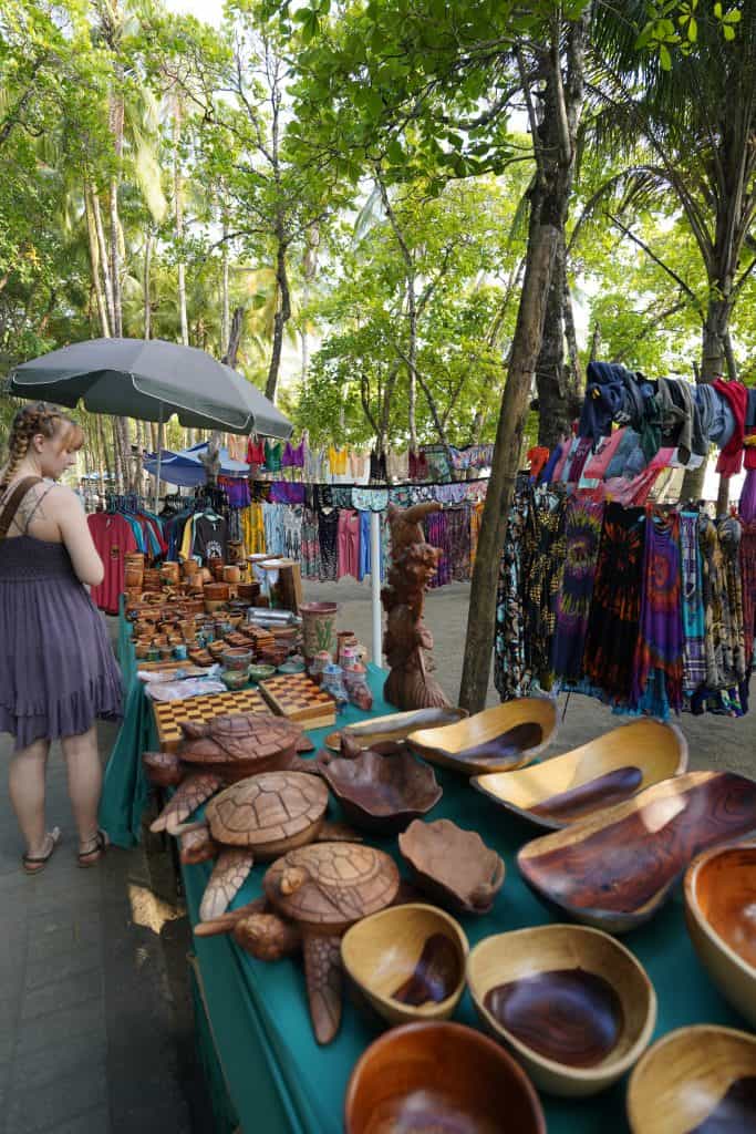 A vibrant outdoor market in Costa Rica, filled with handcrafted wooden bowls, colorful clothing, and unique souvenirs, is perfect for exploring during Costa Rica day trips.