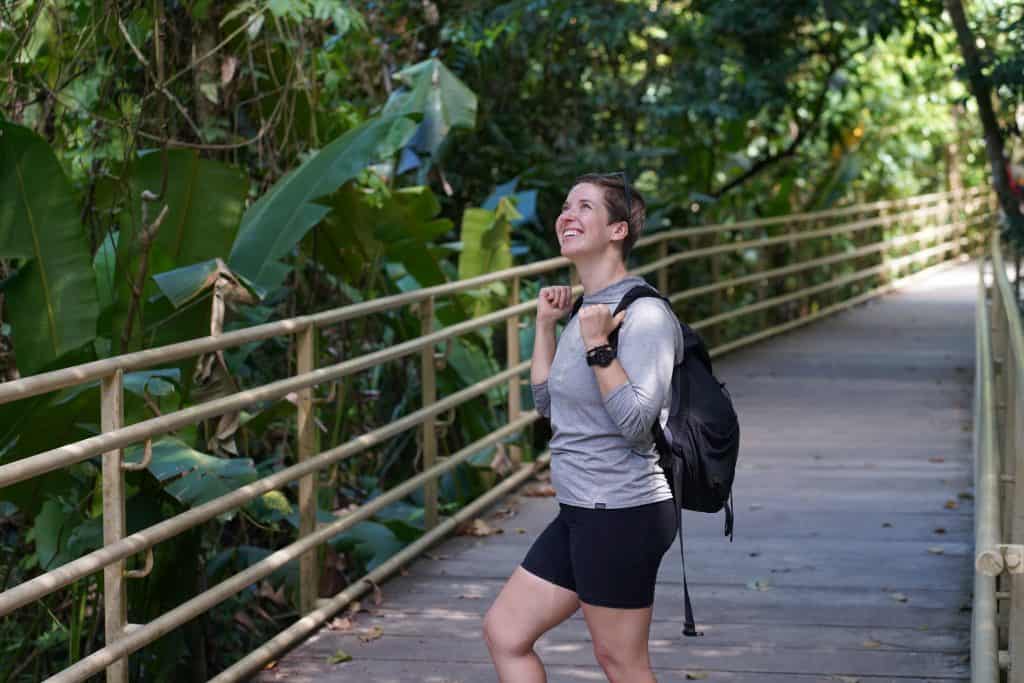 Smiling and enjoying a walk on a raised pathway surrounded by lush tropical plants during one of my Costa Rica day trips.