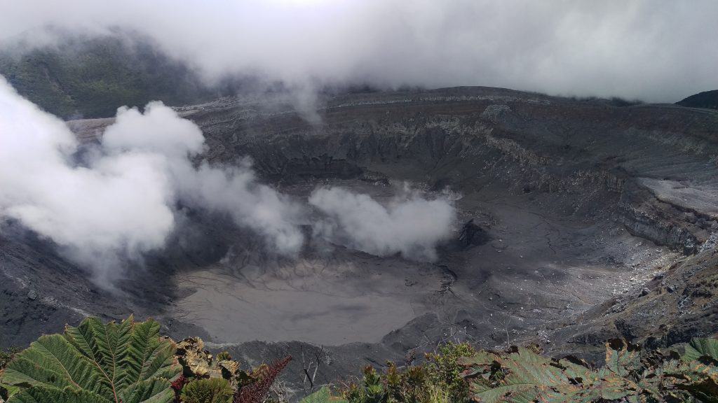 The mist rising from the crater of a volcano, surrounded by rugged, rocky terrain, during one of our Costa Rica day trips.