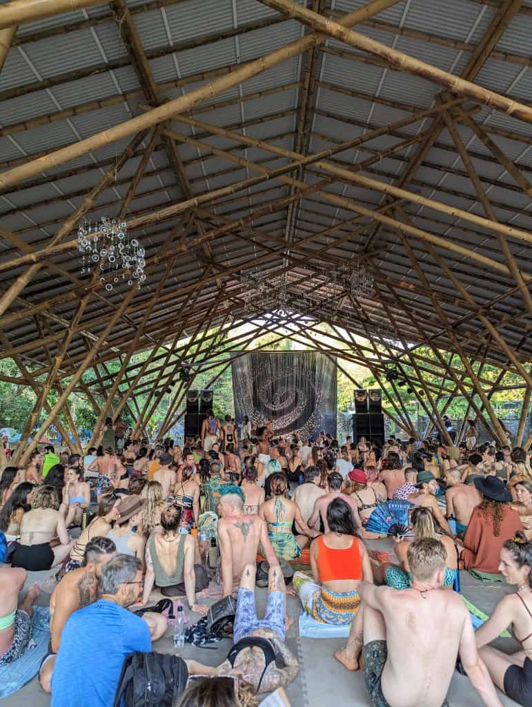 A large group of people gathers inside an open bamboo structure for a community event, highlighting the diverse cultural experiences available during Costa Rica day trips.