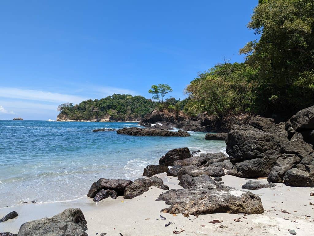 A beautiful, secluded beach with clear blue water and rocky shores, perfect for Costa Rica day trips.