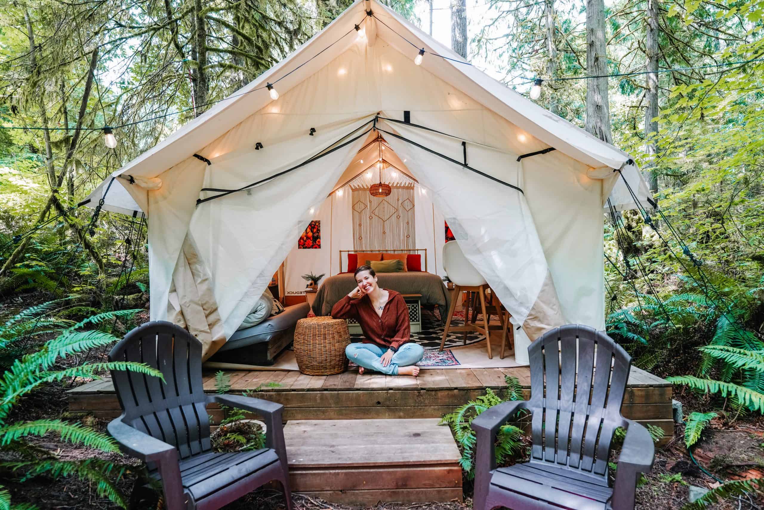 A cozy glamping tent in Washington State, nestled in a forest with string lights, comfortable seating, and that's me relaxing on the wooden deck.