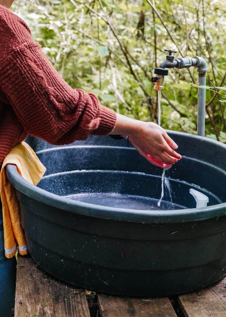 Here I am, washing my hands at an outdoor sink during our glamping trip in Washington State, using fresh water from a tap surrounded by nature.