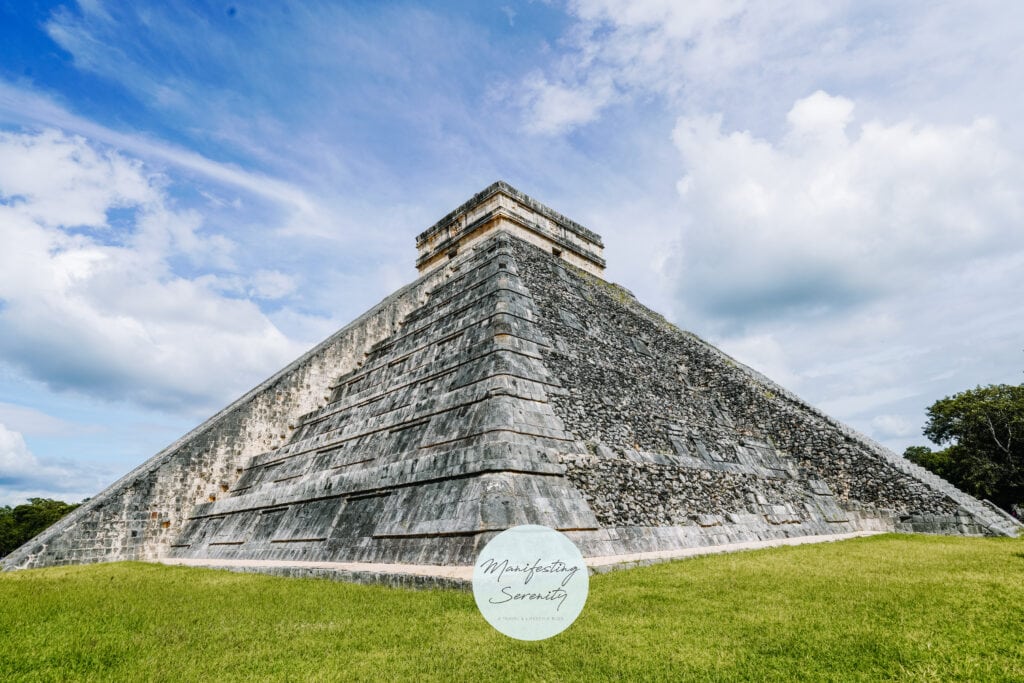 Side view of the iconic pyramid El Castillo on a bright day, with a grassy foreground, perfect for Chichen Itza day trips.