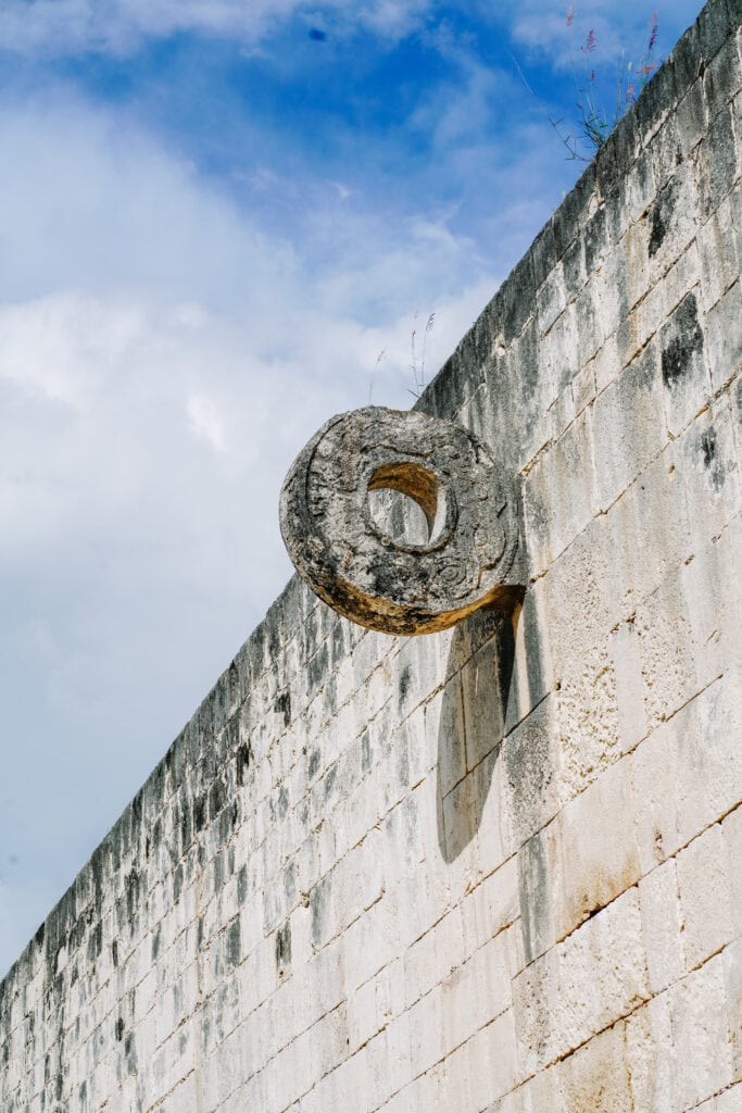 Stone hoop attached to the ancient ball court wall at Chichen Itza, photographed during Chichen Itza day trips under a bright blue sky.